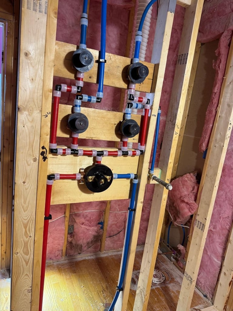 Plumbing system with shut-off valves and PEX tubing mounted on wooden board against pink insulation